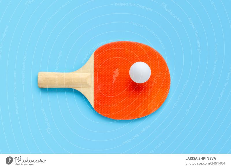 Roter Schläger für Tischtennis mit weißem Ball auf blauem Hintergrund. Tischtennis-Sportgerät in minimalem Stil. Flachlegung, Draufsicht, Kopierraum pong Ping