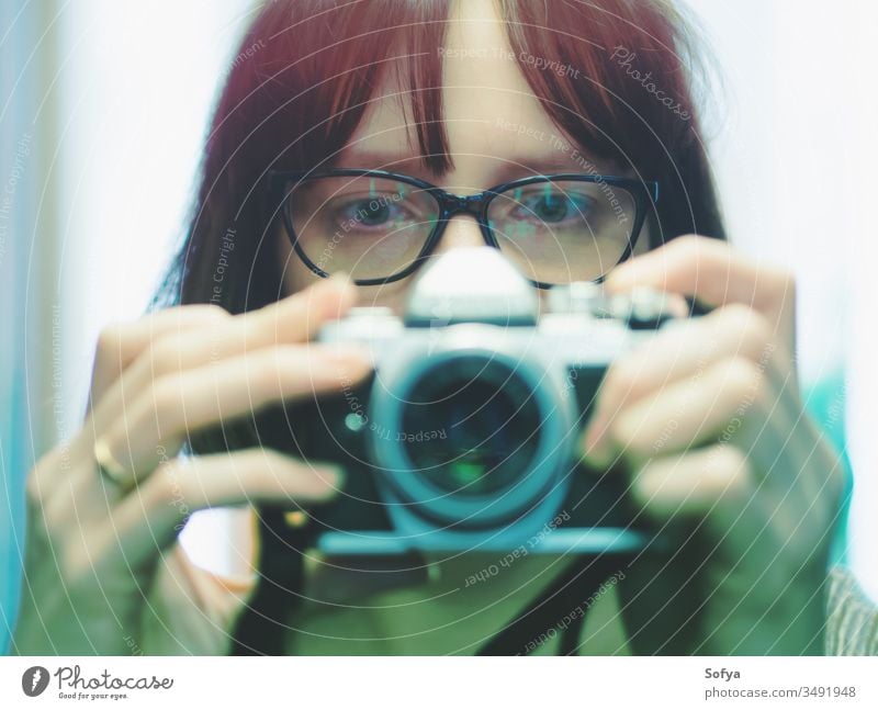 Junges Mädchen mit Brille beim Selbstmachen vor der Kamera Fotokamera Selfie digital Porträt Kino Spiegel Frau Auto spiegellos heben dunkel tragend jung rot