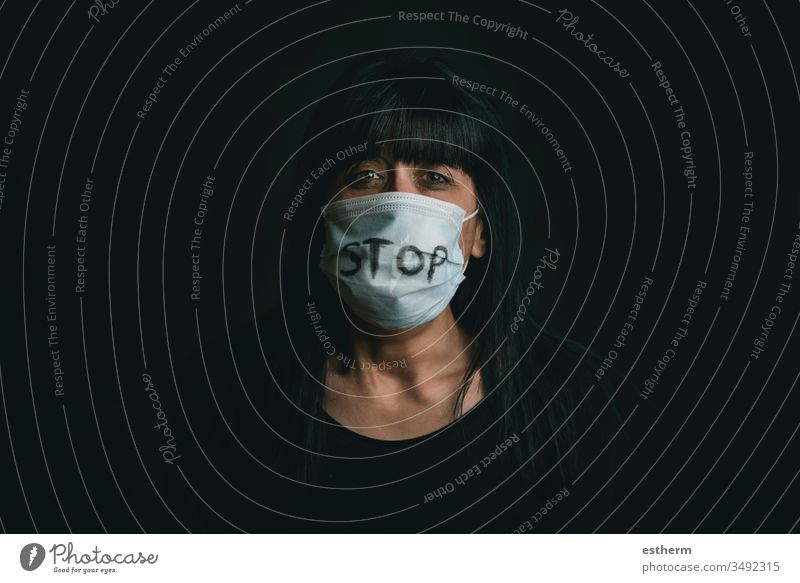 Stop Violence,verängstigte Frau mit medizinischer Maske für Coronavirus-Opfer häuslicher Gewalt Virus Seuche Pandemie Quarantäne Angst Aggression Gefahr