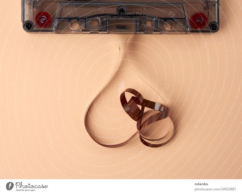 Kassette mit einem braunen Magnetband auf beigem Hintergrund Technik & Technologie Achtziger Gerät Aufzeichnen alt Klebeband retro altehrwürdig Musik magnetisch