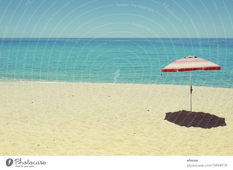 leerer Sandstrand mit einem Sonnenschirm vor blauem Meer bei Sonnenschein Strand Fernweh Menschenleer Wasser verwaist Sommer Ferien & Urlaub & Reisen Küste