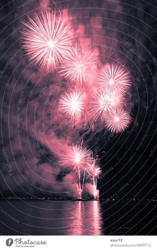 Luxus-Feuerwerksveranstaltung Himmel-Wasser-Meeresschau mit roten Sternen. Hochwertiges Unterhaltungs-Zaubersternfeuerwerk z.B. zu Silvester oder zur Feier des Unabhängigkeitstages. Schöne Spiegelungen auf der Seeoberfläche
