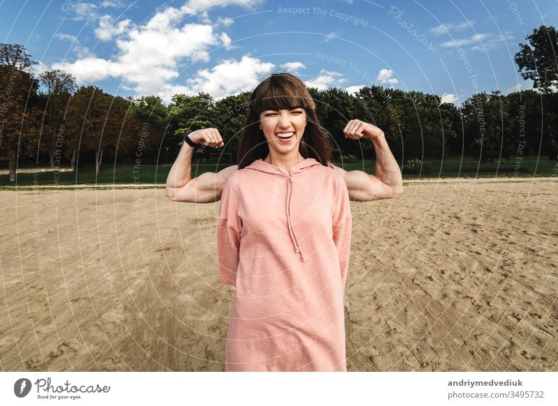 Sportlich-energetische athletische Frau trägt ein rosa Sporthöschen, das ihren Bizeps zeigt, sie mag Sport und einen aktiven Lebensstil. Athlet Muskel Fitness