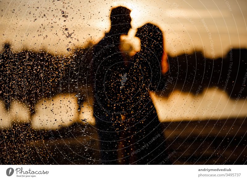 Silhouette eines liebenden Paares, das sich bei Sonnenuntergang auf dem See umarmt. Schönes verliebtes junges Paar, das bei Sonnenuntergang in den Strahlen des hellen Lichts am Ufer des Sees spazieren geht. copy space. selective focus