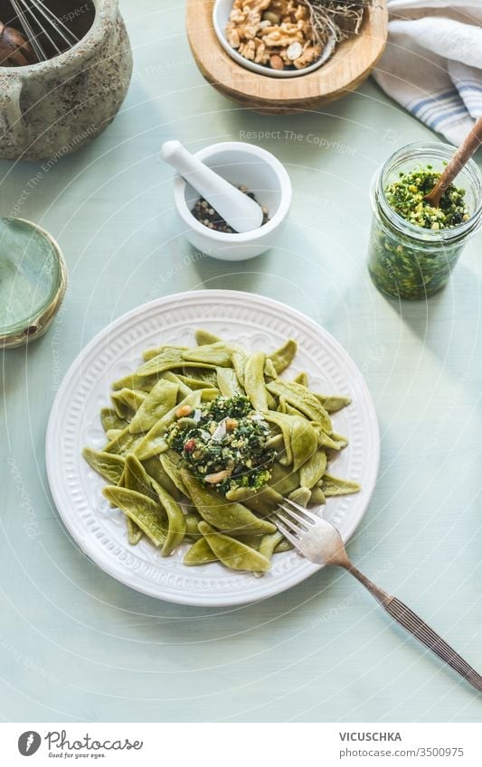 Draufsicht auf einen gesunden Mittagstisch mit grünen Nudeln oder Pasta und Pesto auf hellem Hintergrund. Ansicht von oben. Gesundes vegetarisches Essen