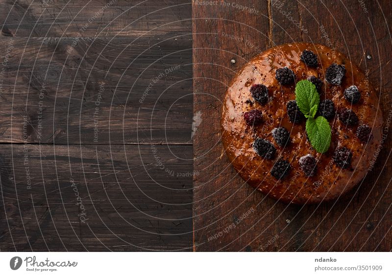 gebackener runder Biskuitkuchen mit Nüssen und Beeren belegt, brauner Holztisch schwarz Brot Kuchen Nahaufnahme Koch Essen zubereiten Küche dunkel lecker