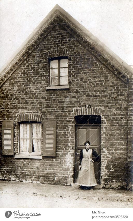 Oma ihr Häusschen Nachkriegszeit Vergangenheit Nostalgie Erinnerung analog Eingangstür Haus Großmutter Leben alt Tür Kittel Schürze stehen Schwarzweißfoto