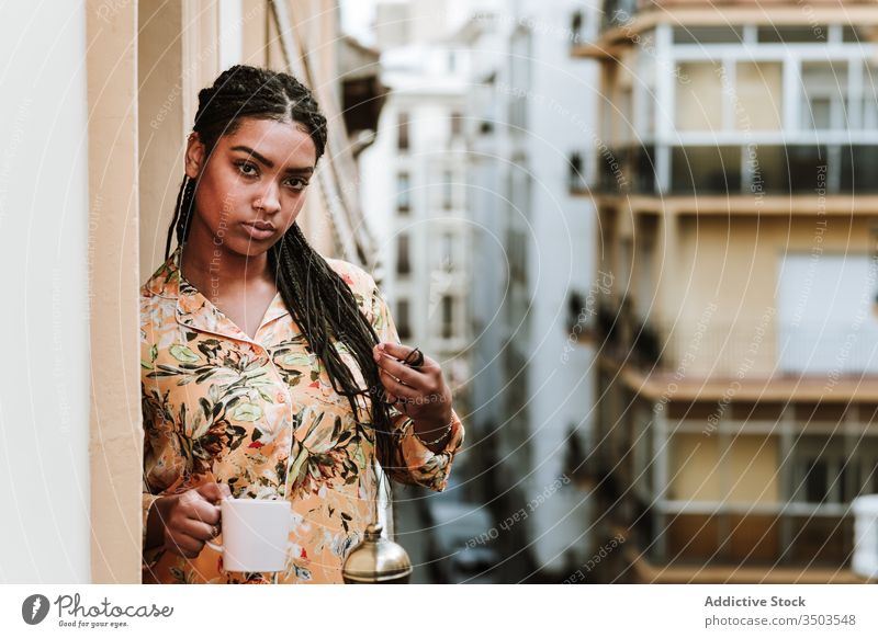 Junge Frau mit Tasse Kaffee auf dem Balkon stehend Windstille trinken lässig heimwärts ruhig nachdenklich sich[Akk] entspannen jung Afroamerikaner schwarz
