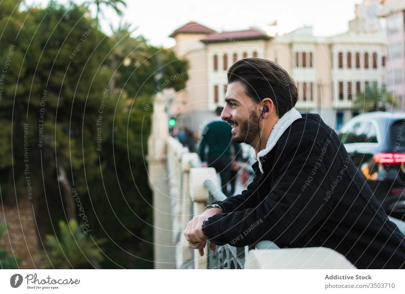 Glücklicher Mann mit Kopfhörern steht auf Stadtbrücke Großstadt zuhören Straße Brücke ruhen sich[Akk] entspannen genießen Musik Lifestyle männlich ethnisch