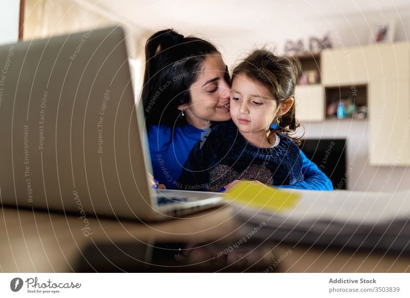 Mutter spielt mit Tochter und arbeitet an Fernprojekt spielen Umarmung Arbeit Laptop benutzend abgelegen heimwärts belästigen Liebe Frau Mädchen wenig