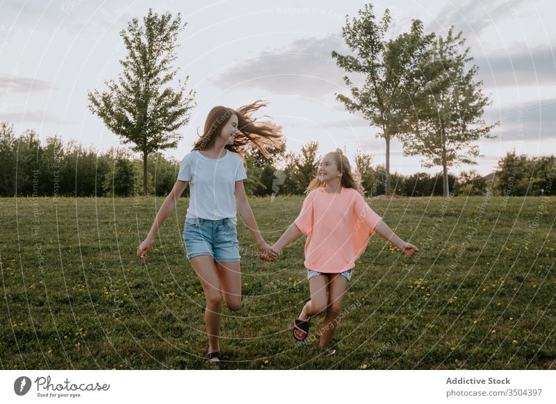 Glückliche Schwestern amüsieren sich im Sommer auf dem Land Kind Natur Zusammensein Spaß haben Mädchen Landschaft heiter laufen Teenager grün Wiese