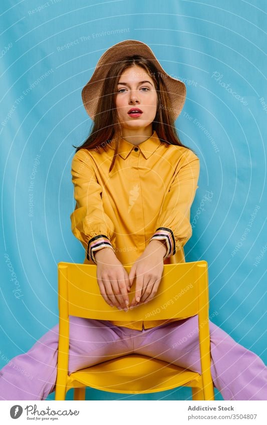 Stilvolles weibliches Modell auf Stuhl sitzend Frau trendy farbenfroh Outfit jung selbstbewusst Farbe Hut Sommer sinnlich urban tausendjährig Kälte ernst