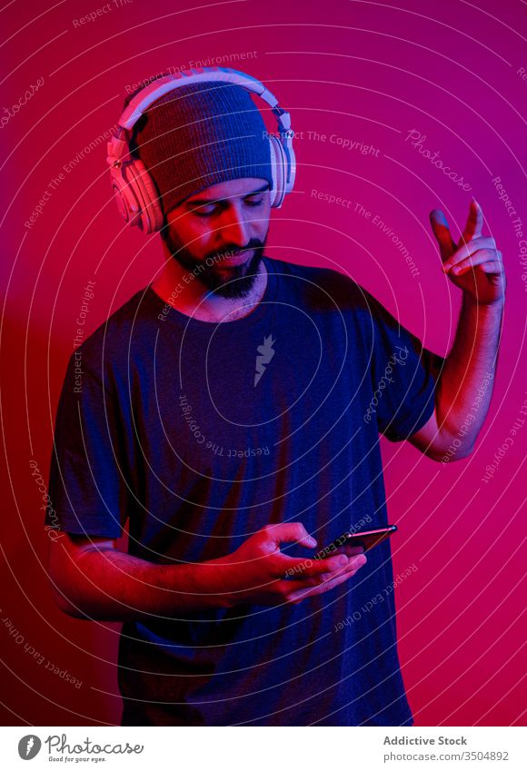 Der moderne Mensch benutzt ein Smartphone und hört Musik Mann zuhören benutzend Shaka-Zeichen Stil Handy Rotlicht männlich Gerät Apparatur gestikulieren