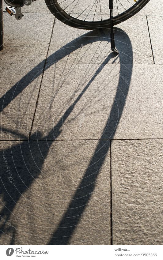 Mein Ständer wirft sehr lange Schatten Rad Fahrrad Speichen Steinplatten sonnig Fahrradständer