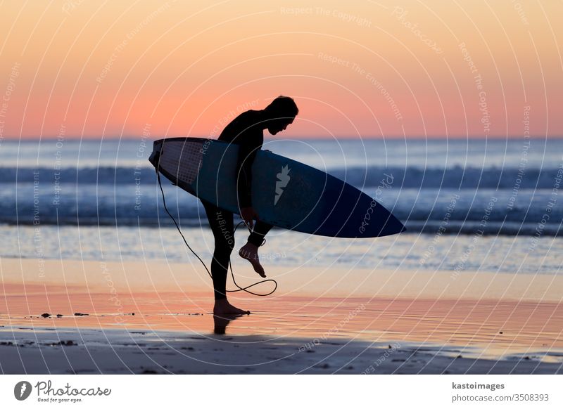 Silhouette eines Surfers am Strand mit Surfbrett. Sonnenuntergang Sommer Sport Mann Brandung Surfen Meer Wasser Natur Sonnenaufgang aktiv Spaß Holzplatte Sand