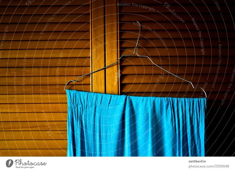 Blaues Tuch auf einem Bügel bügel tuch handtuch lamellen lamellentür menchenleer haushalt raum schrank schranktür trocknen wohnen wohnung wäsche zimmer holz