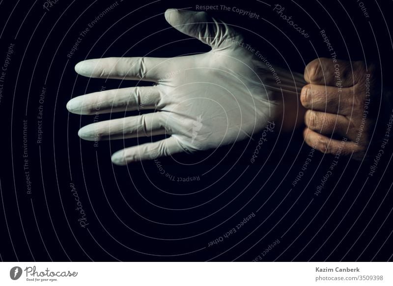Nahaufnahme eines Heilpraktikers, der seine Operationshandschuhe vor dunklem Hintergrund ausstreckt Handschuh tragend Hände Korona Coronavirus Virus Hygiene