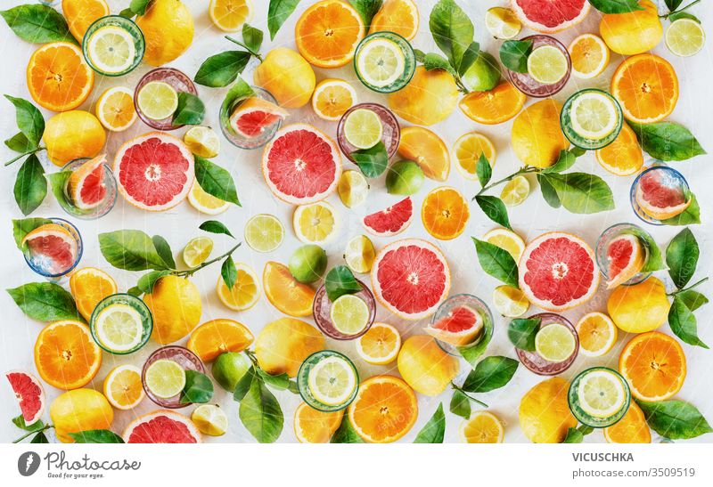 Zitrusfrüchte-Hintergrund, hergestellt aus ganzen, halben und Scheiben verschiedener Zitrusfrüchte mit grünen Blättern. Ansicht von oben. Flach gelegt. Gesunde Ernährung. Vitamine. Zutaten zum Trinken.