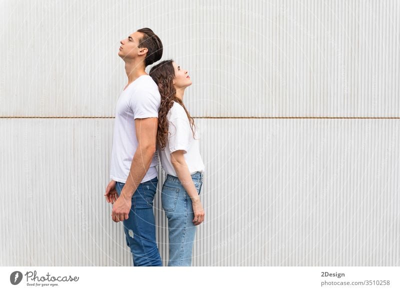 Junges Paar steht Rücken an Rücken gegen die weiße Stadtmauer Frau Mann jung Menschen männlich Mädchen Glück 2 Porträt Hintergrund Stehen schön Freizeitkleidung