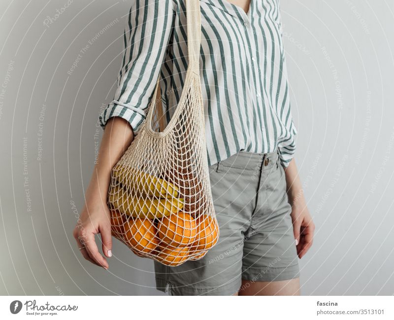 Frau stehend mit Netztasche auf der Schulter ineinander greifen Tasche keine Verschwendung null Abfall Früchte kaufen lässig Stil modern Konzept Gewebe Frucht