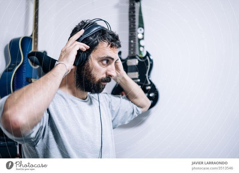 Arbeitender Toningenieur mit Kopfhörer im Heimstudio. Mann Komponist Lernen Gitarren Künstler Audio Rücken Hintergründe digital Entertainment Computer