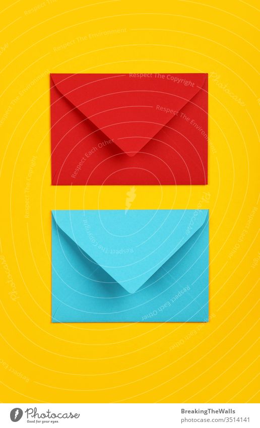 Zwei geschlossene Umschläge aus blauem und rotem Papier auf gelb Kuvert zwei Pastell lebhaft Hintergrund Nahaufnahme Farbe farbenfroh mehrfarbig schließen