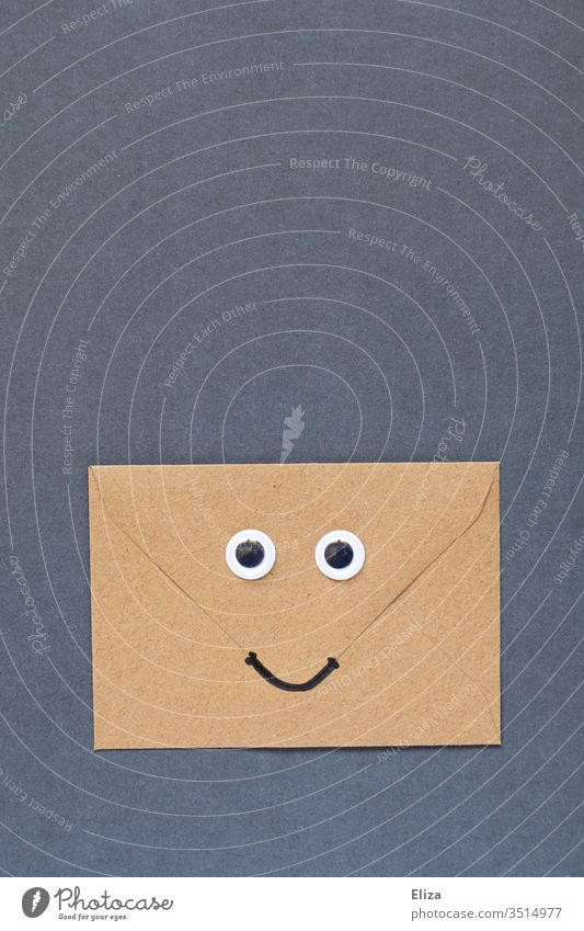 Ein brauner freundlich lächelnder Briefumschlag mit Augen und Mund Wackelaugen gute Nachrichten Freude Gesicht Lächeln Post Umschlag Kommunizieren Kommunikation