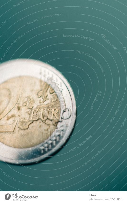 Nahaufnahme einer Zwei Euro Münze vor türkisem Hintergrund; Geld, Finanzen Makroaufnahme Eurostück hell Finazen Sparen Kapitalwirtschaft Geldmünzen Bargeld