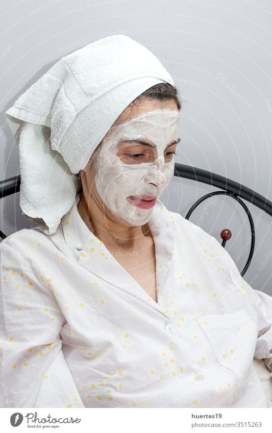 Reife Frau pflegt ihr Gesicht mit einer Gesichtsmaske im Bett mit Hund Schönheit Behandlung Gesichtsbehandlung Mundschutz reif Laptop covid-19 Coronavirus