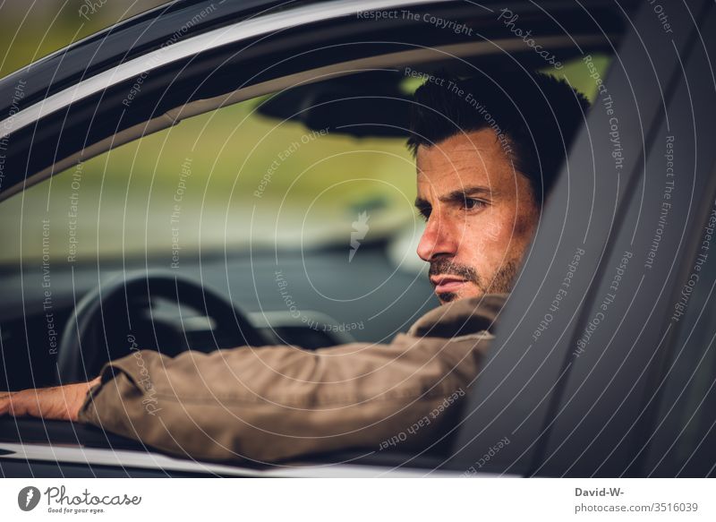 Mann sitzt im Auto und schaut ernst aus dem Fenster blick nach draussen Rückspiegel Spiegel blick zurück Straßenverkehr Autofenster offen genervt sauer böse