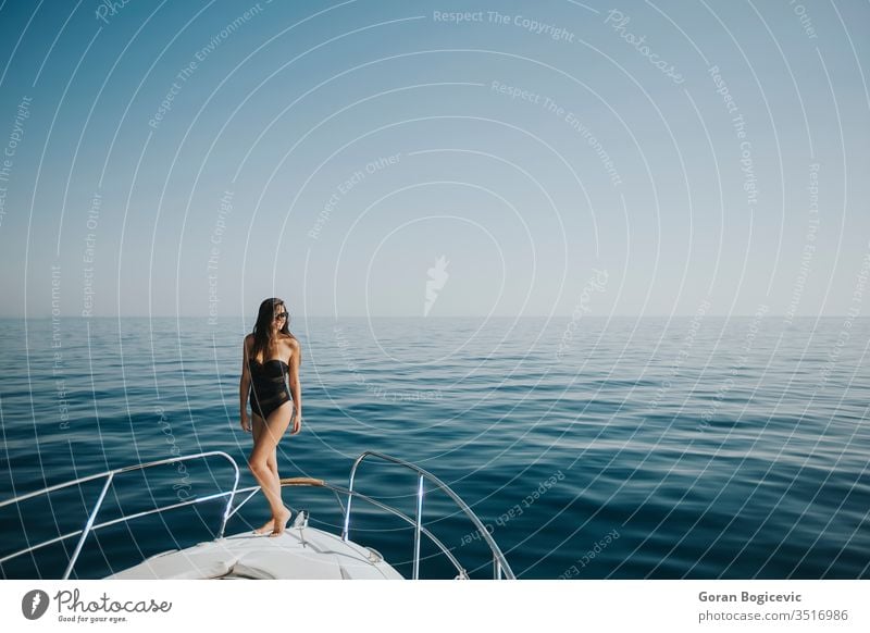 Junge Frau in Badebekleidung steht an der Vorderseite einer Yacht Erwachsener attraktiv schön Schönheit Bikini blau Boot Bootfahren Körper brünett Kaukasier