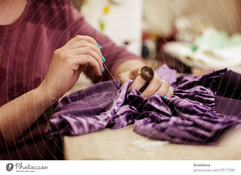 Weibliche Hände nähen Stoff mit der Nadel am Arbeitsplatz der Näherin. Seitenansicht Nadelbett Helfer Ring Faser Stickereien Kreide Schneiden Briefpapiermesser