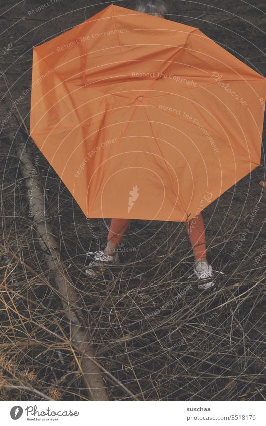 kind versteckt sich hinter einem kaputten orangefarbenen regenschirm im wald und nur die füße gucken raus .. Kind Beine Füße Regenschirm Ast Baum Wald Zweige