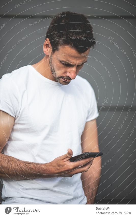 junger Mann schaut auf sein Handy haltend Tippen Sucht suchtgefahr Informationstechnologie Internet Mobilität schreiben Nachricht Message Finger lässig