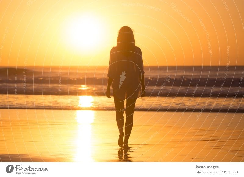 Dame beim Spaziergang am Sandstrand im Sonnenuntergang. Strand MEER Frau Sommer Fußspur Fußtritt Landschaft Küstenlinie Urlaub Wasser Natur Wellen schön Meer