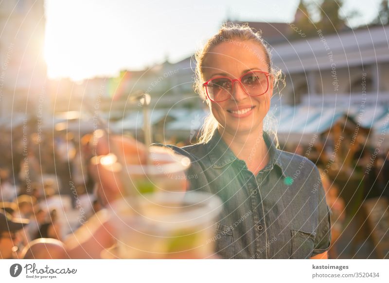 Hübsches junges Mädchen stößt auf städtisches Ereignis im Freien an. Veranstaltung Stadtfest Zuprosten trinken Frau Menschen Musik Alkohol Spaß Fröhlichkeit