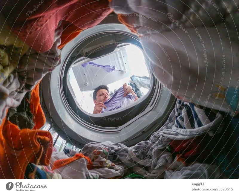 Bärtiger Mann benutzt Waschmaschine zu Hause allein Appartement Bekleidung Bachelor Vollbart tragen Arbeit Hausarbeiten Reinigen Kleidung täglich Typ