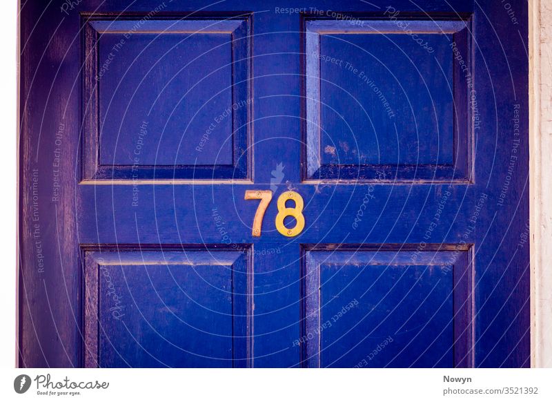 Hausnummer 78 an einer dunkelblau verwitterten und abgenutzten hölzernen Haustür 78 Zahl Adresse britannien klassisch stilvoll abschließen Nahaufnahme