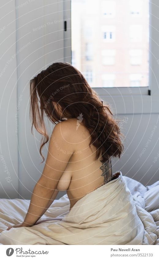 Sexy tätowierte Frau mit schönen langen Haaren sitzt auf dem Bett nackt allein Mädchen traurig heimwärts im Innenbereich LAZY Orgasmus sexy unbekleidet