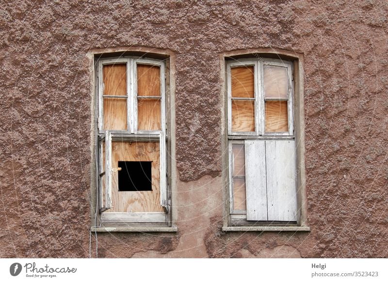 alt | Fassade eines alten Gebäudes mit kaputten Fenstern, die mit Brettern verschlossen sind, eins hat ein Guckloch Bauwerk geöffnet zugenagelt Haus