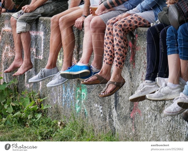 junge Leute chillen auf Mauer und lassen die Füße baumeln Beine sitzen viele Festival Barfuß jugend Sommer freizeit Freizeit & Hobby Fuß warten anonym