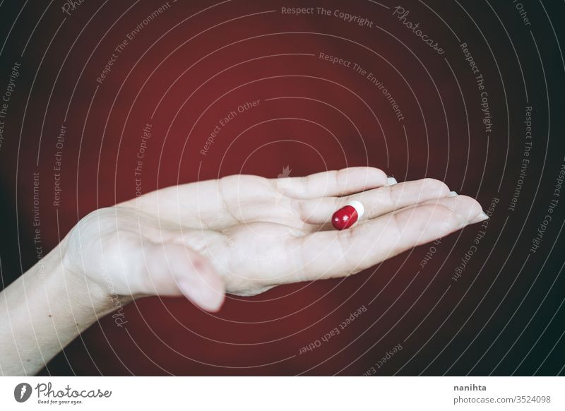 Junge Frau hält in der Hand eine weiß-rote Pille Tablette Medikament Medizin Virus Süchtige süchtig machend Sucht Schmerztablette Schmerzmittel abschließen
