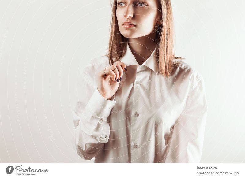 Porträt einer jungen erwachsenen Frau, die mit der Hand einen Kragen eines weißen Hemdes hält, selektiver Fokus Aussehen saubere Haut Naturkosmetik Maniküre