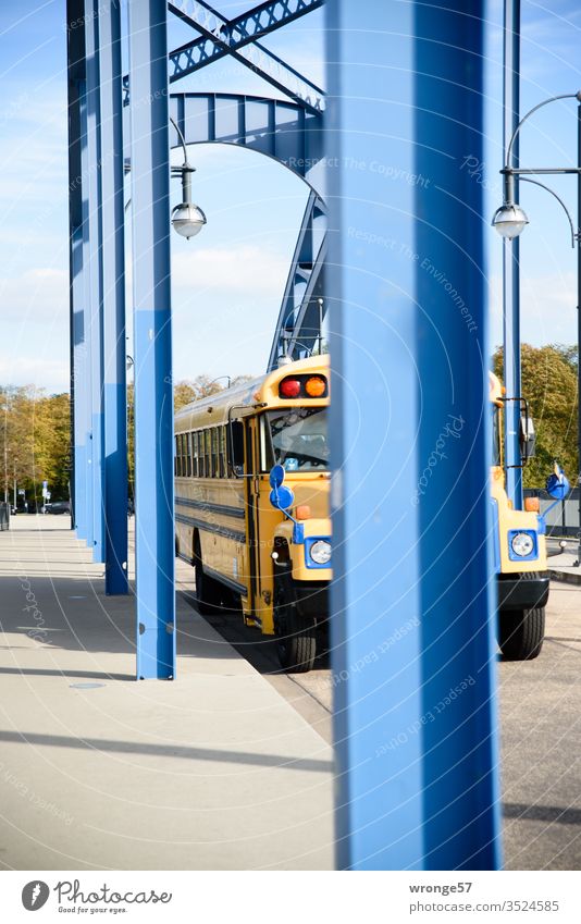 Amerikanischer Schulbus zwischen blauen Pfeilern einer Bogenbrücke US Schulbus US-Schulbus Brücke Brückenpfeiler reisen fahren Farbfoto Außenaufnahme Verkehr