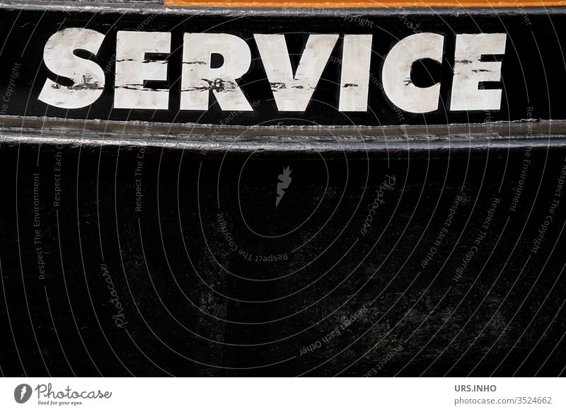 weißer Schriftzug SERVICE in Großbuchstaben auf schwarzem Hintergrund Service Text Aufschrift Schriftzechen Schiffsrumpf Boot schmutziz Buchstaben