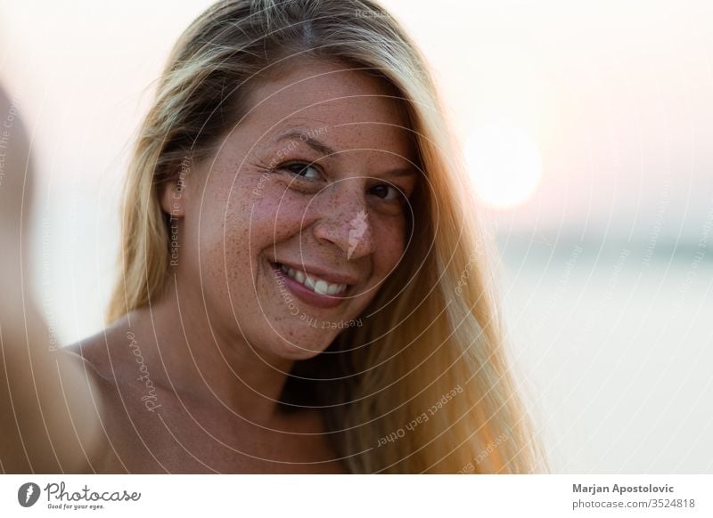 Junge gebräunte Frau bei Sonnenuntergang ein Selfie Erwachsener attraktiv Strand schön Schönheit blond Fotokamera sorgenfrei lässig Kaukasier heiter Teint