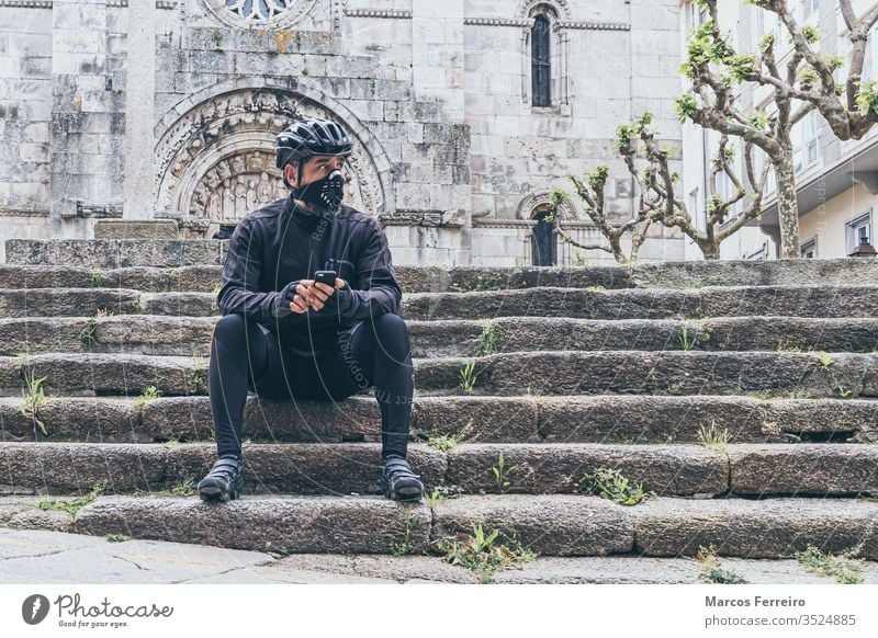 erwachsener Mann mit Fahrradkleidung und Maske in der Stadt Sport Viren Corona-Virus Atemwegserkrankungen Gesichtsmaske außerhalb COVID Kaukasier