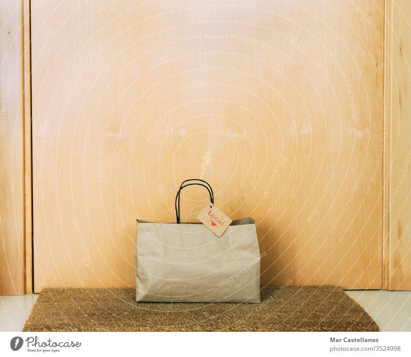 Einkaufstasche aus Papier mit Kartonaufkleber an der Haustür des Hauses. Konzept des Einkaufens. Tasche kennzeichnen Tür Eingang Unterlage recycelbar Verkauf