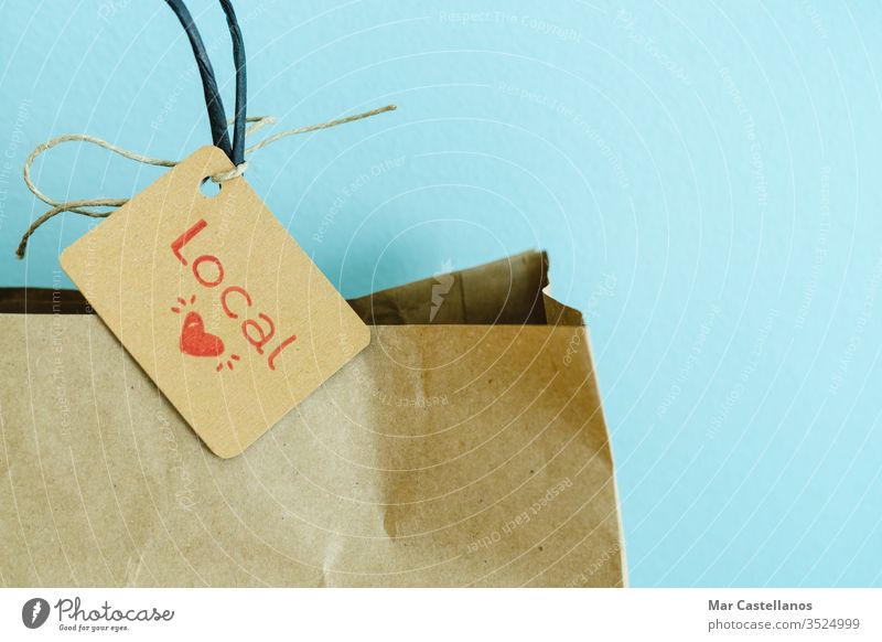Einkaufstasche aus Papier auf blauem Hintergrund. Etikett mit Herz und Text LOCAL. Einkaufskonzept. kaufen Tasche kennzeichnen Blauer Hintergrund recycelbar