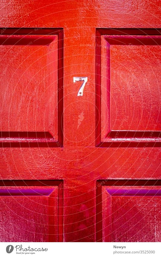 Hausnummer 7 an einer roten Holzhaustür mit Glück 7 Zahl Adresse britannien Burgunder klassisch stilvoll abschließen Nahaufnahme Textfreiraum copyspae